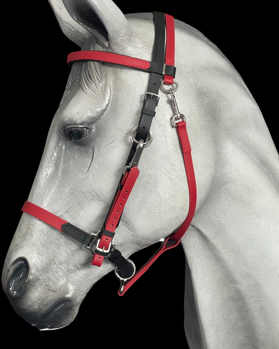 A detailed image of a grey horse mannequin highlights the LS Enduro - Design your own bridle from LS Equestrian, featuring vibrant black and red colors with shiny stainless steel fittings against a black background. The bridle is custom-designed with adjustable straps and polished metal buckles.