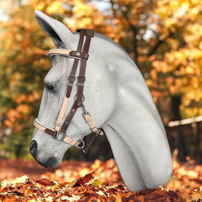 A realistic gray horse head sculpture is adorned with an LS Deux 2 Part Bridle Padded - Design your own from LS Equestrian, crafted from Beta BioThane, all set against a vivid autumn backdrop featuring colorful fallen leaves and trees. This piece is handmade in New Zealand.